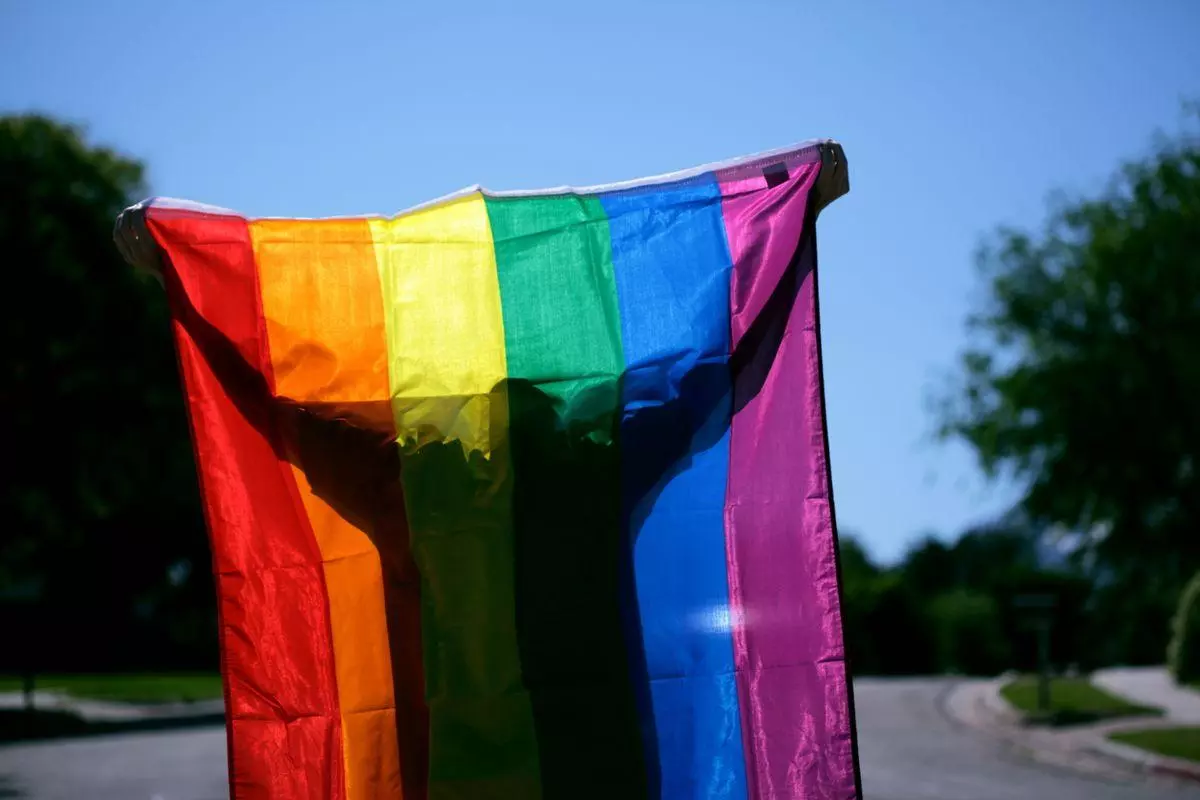 Une personne tenant un drapeau arc-en-ciel